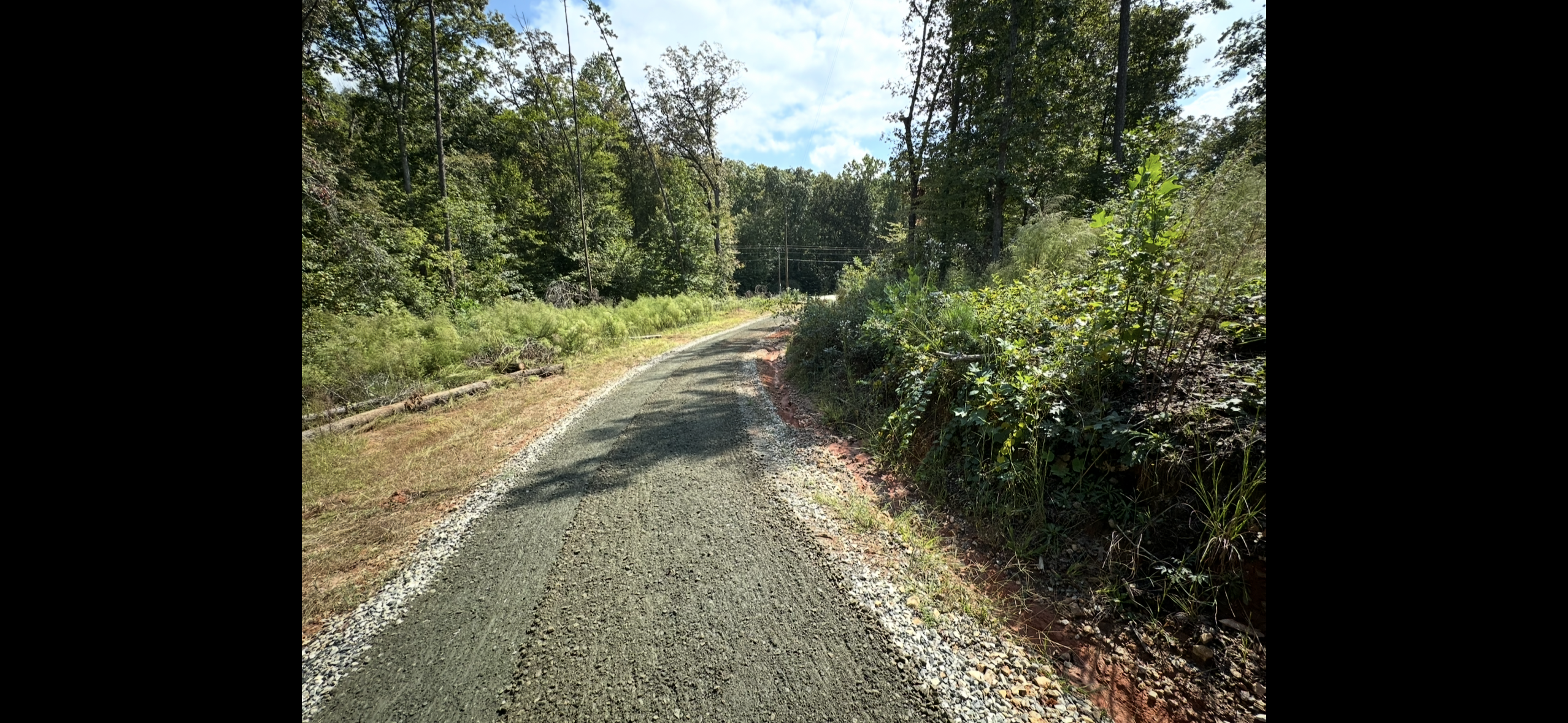 Completed gravel driveway restoration through wooded property